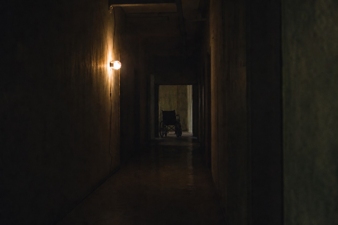 Dark corridor with a flickering lamp inside the haunted hospital attraction