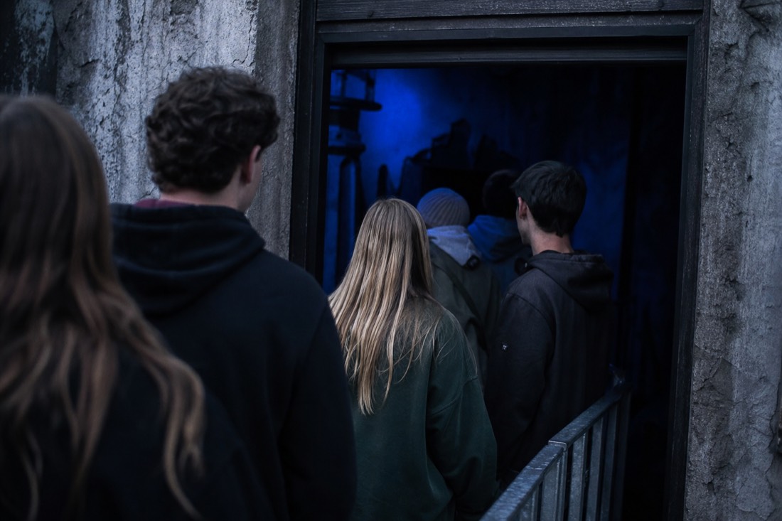 Visitors hesitating at the dark entrance of a horror walk-through