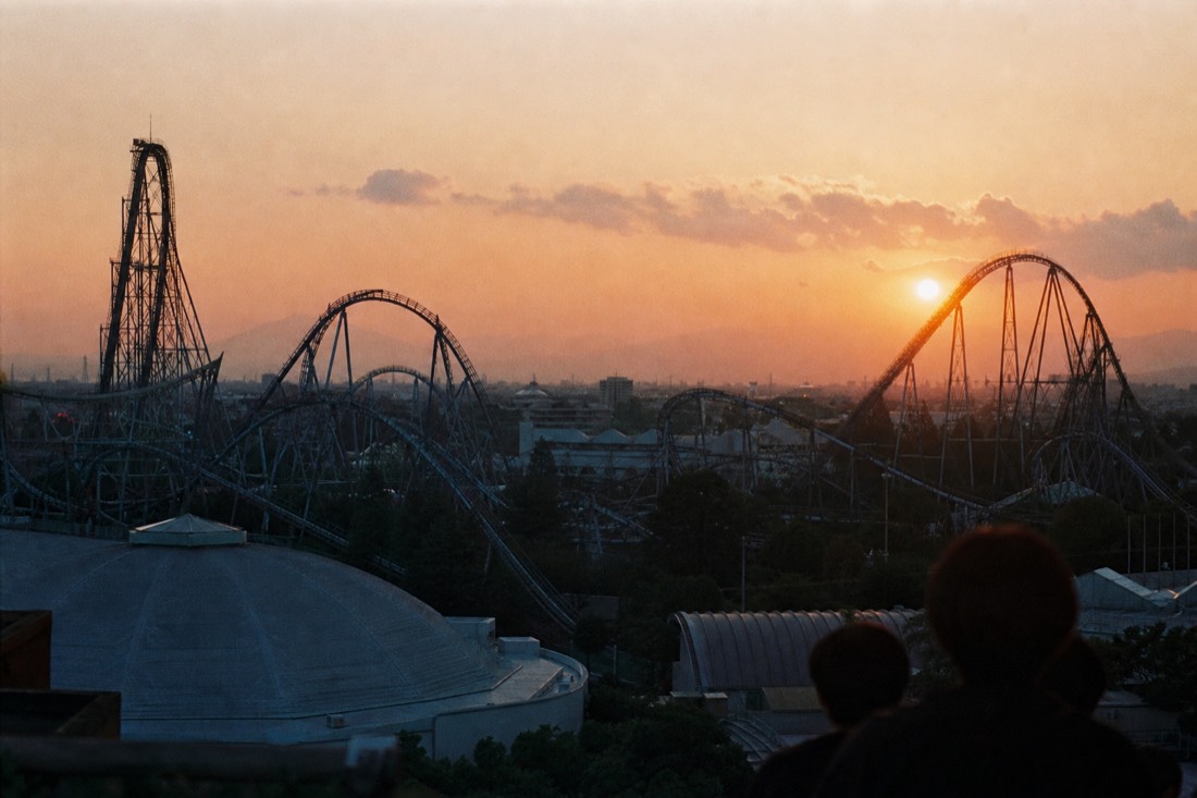 Coaster silhouettes over a Japanese amusement park at sunset