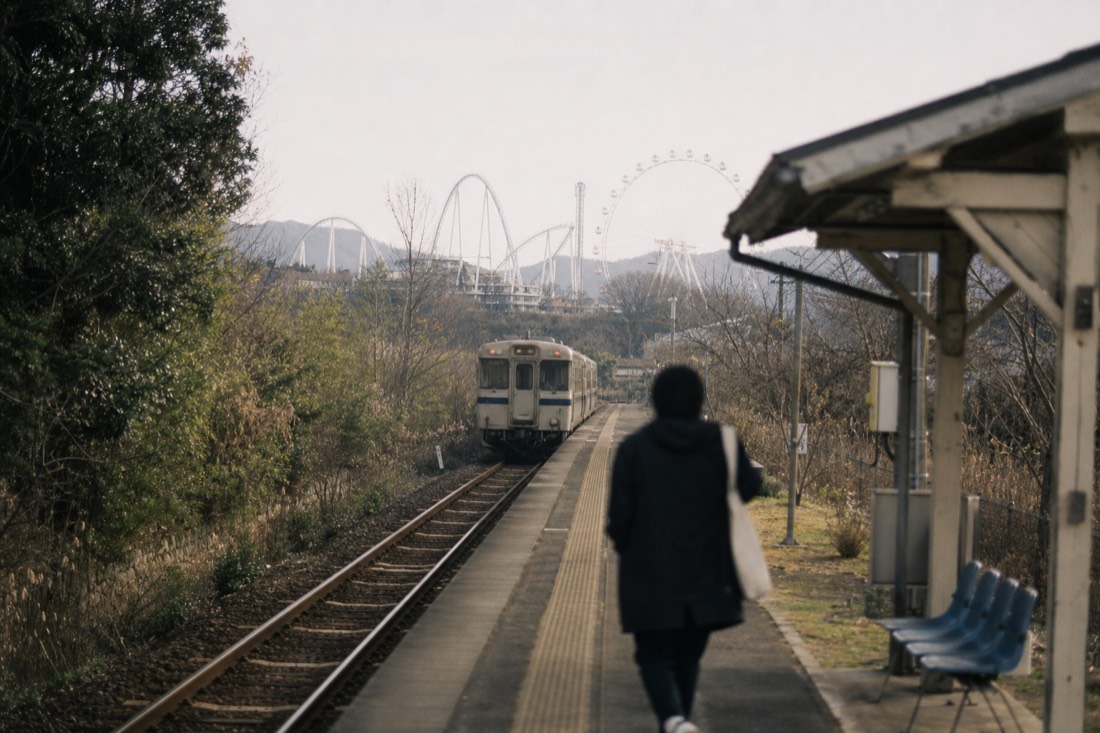 Rural railway platform near Fuji-Q Highland with park structures in the distance