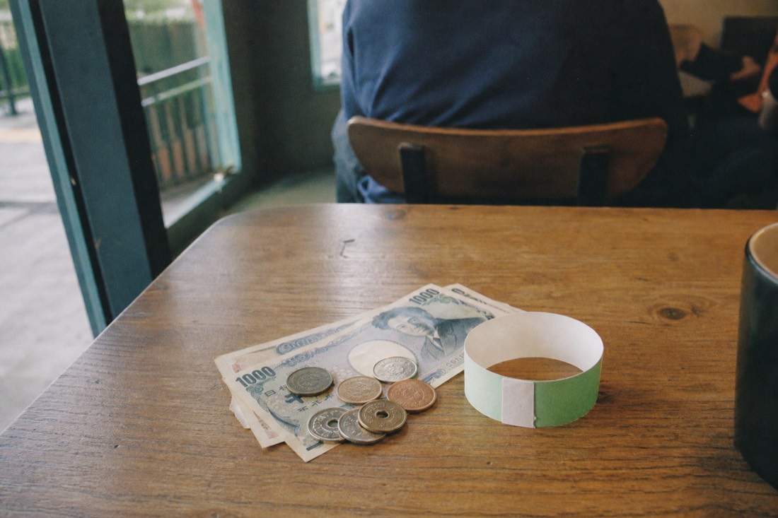 Japanese yen and a day-pass wristband on a table, budgeting a Fuji-Q day