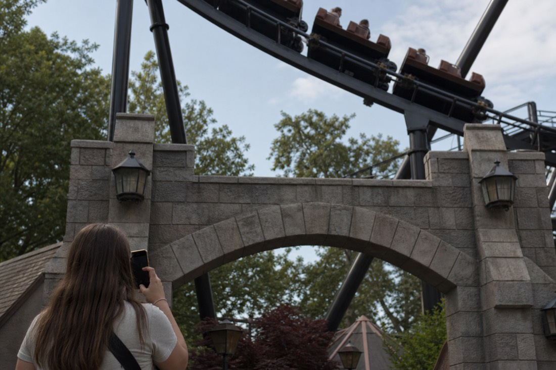 Visitor checking a phone near a Fuji-Q ride entrance arch