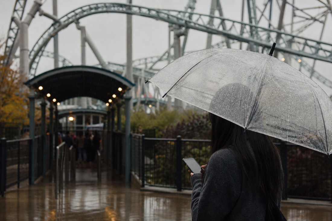 Visitor checking the live ride status on a phone in light rain at Fuji-Q Highland