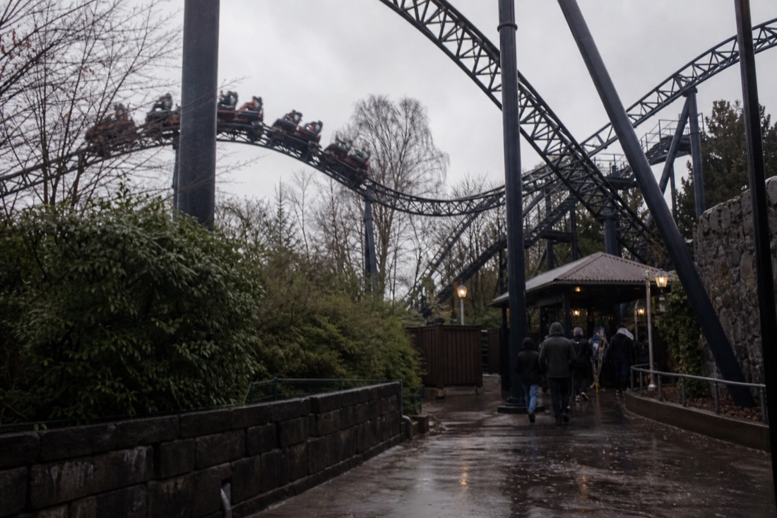 A nearly empty Fuji-Q Highland path in drizzle with a coaster still running behind