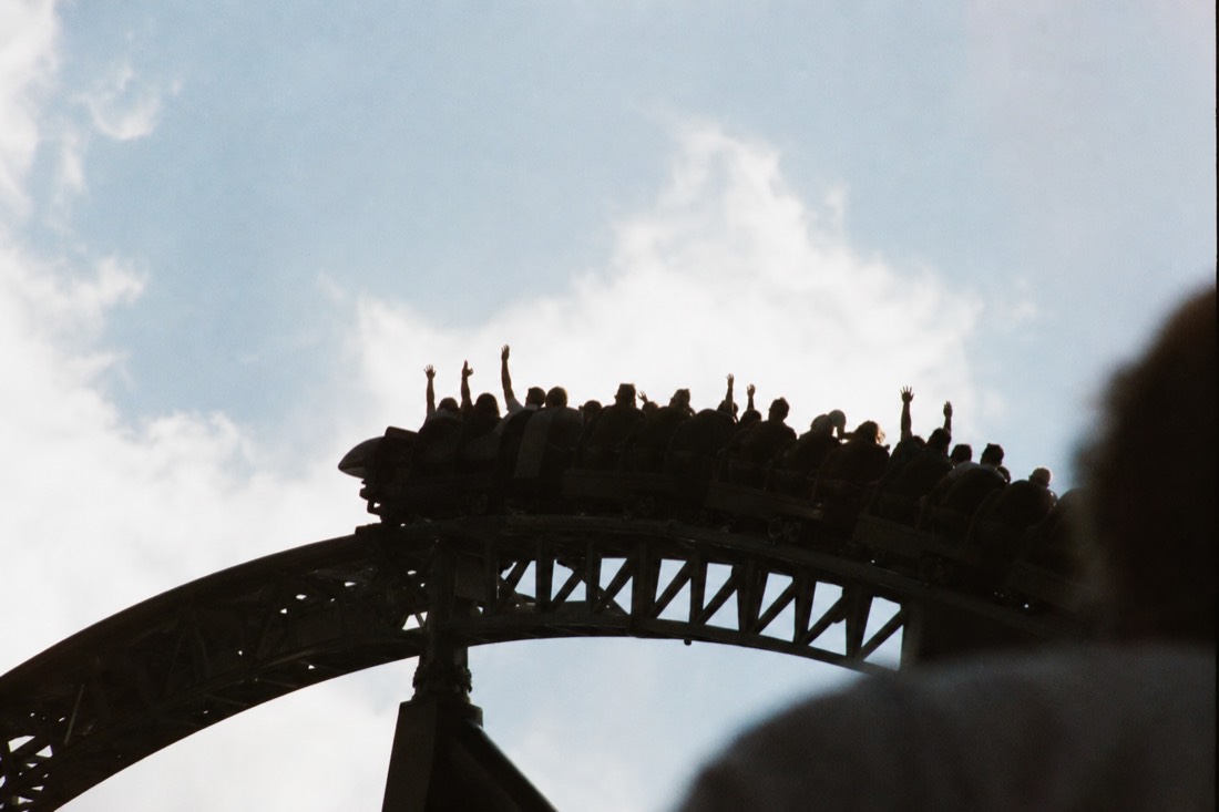Riders' silhouettes with arms raised on a Fuji-Q Highland coaster hill